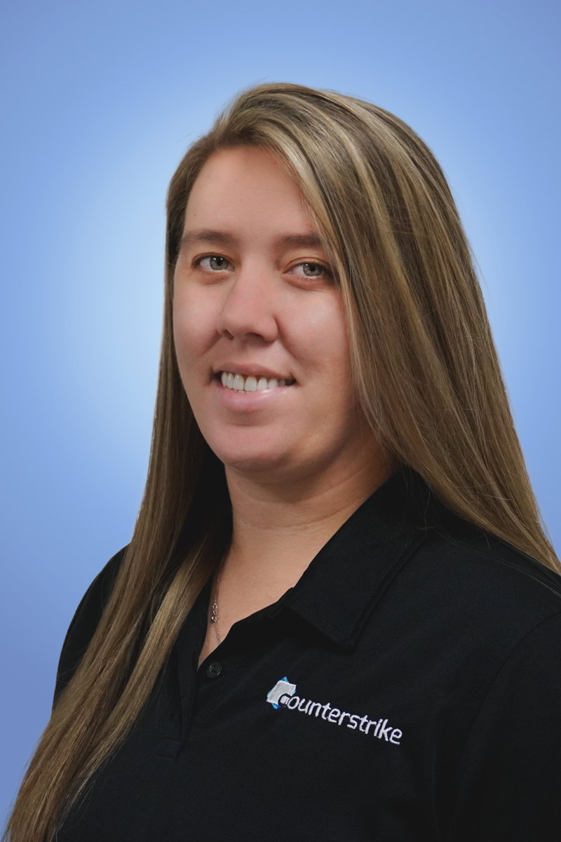 Portrait of a woman with long light brown hair wearing a black polo shirt with the Counterstrike logo, against a blue gradient background.