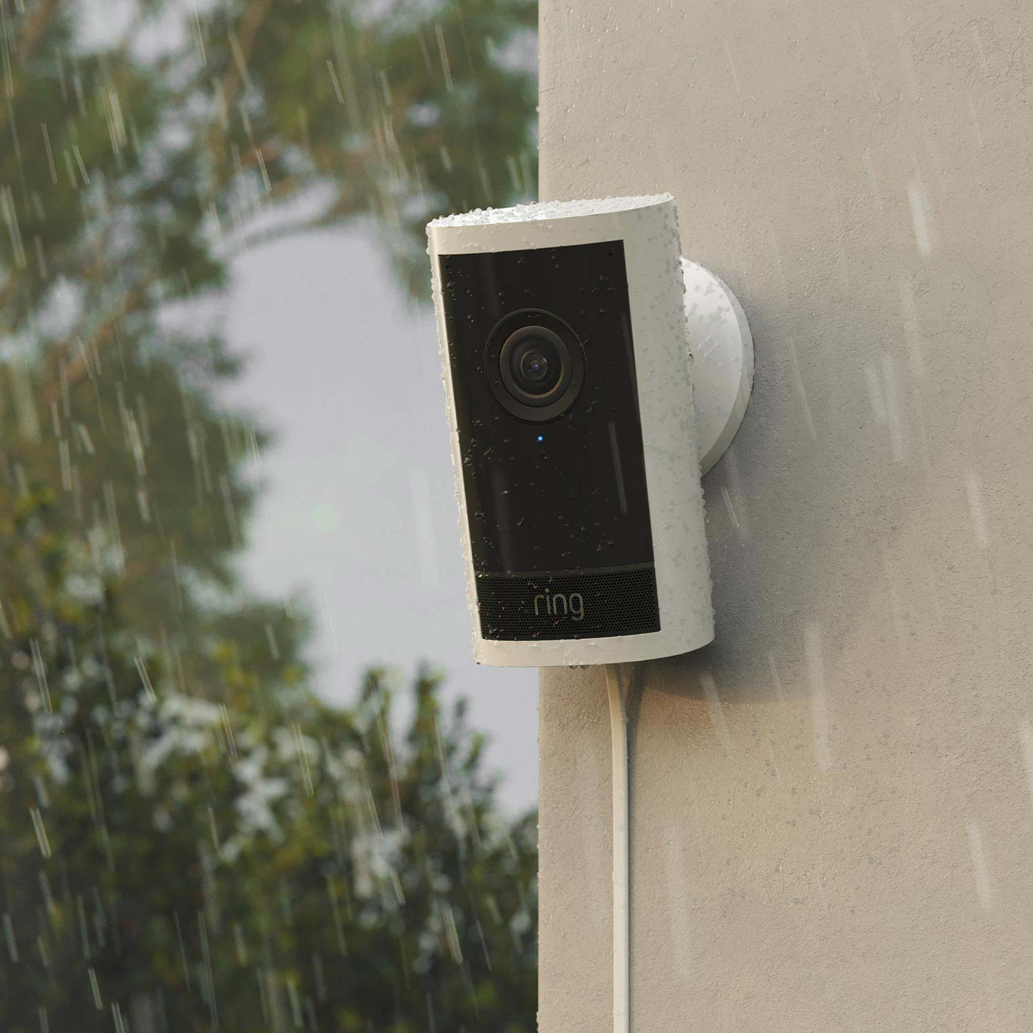 Rainy day exterior with a Ring video doorbell mounted on a beige wall.